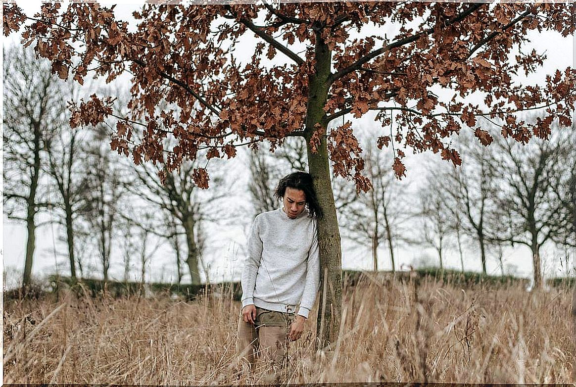 Boy leaning on tree thinking that I feel undervalued by others