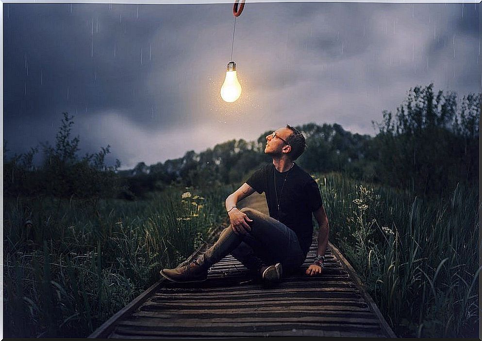 Boy looking at a light bulb that turns on